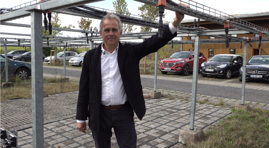 Pierre Georgel devant le simulateur de pluie pour parking perméable : dispositif d'aspersion au-dessus de places de parkings